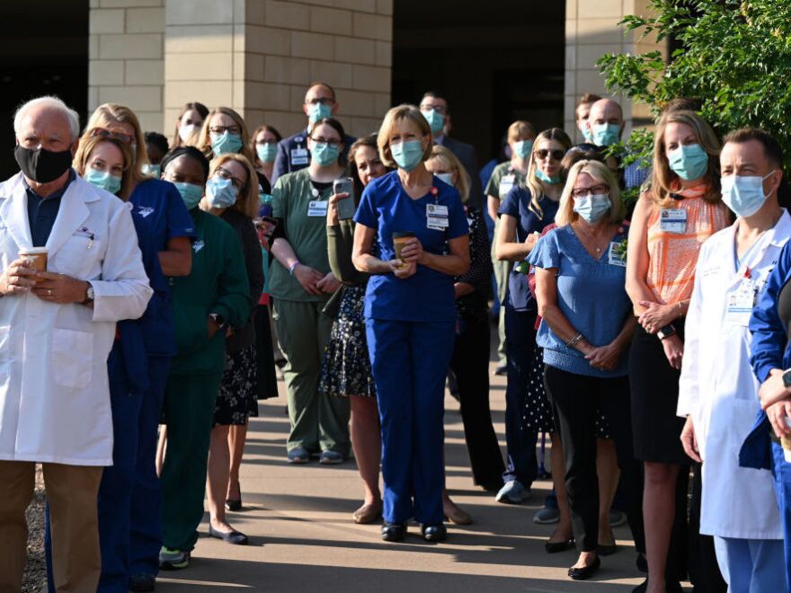 Frontline workers at a medical center in Aurora, Colo., gather for a COVID-19 memorial on Thursday, July 15, to commemorate the lives lost to the pandemic. New estimates say many thousands more will die in the U.S. this summer and fall.