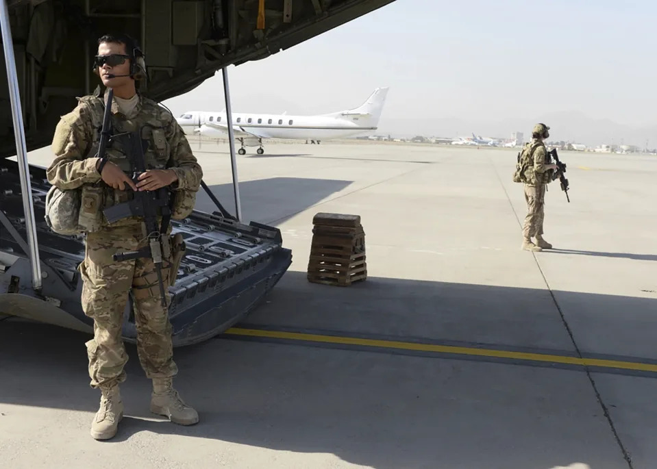 Wilmer Puello-Mota, left, a member of the U.S. Air Force, provides security at Hamid Karzai International Airport in Kabul, Afghanistan, on Aug. 28, 2015. Puello-Mota, a U.S. Air Force veteran and former elected official in Massachusetts who fled the U.S. after being charged with possessing sexually explicit images of a child, told his lawyer he joined Russia’s army, and video appears to show him signing documents in a military enlistment office in Siberia, Russia. (Senior Airman Cierra Presentado/U.S. Air Force via AP)
