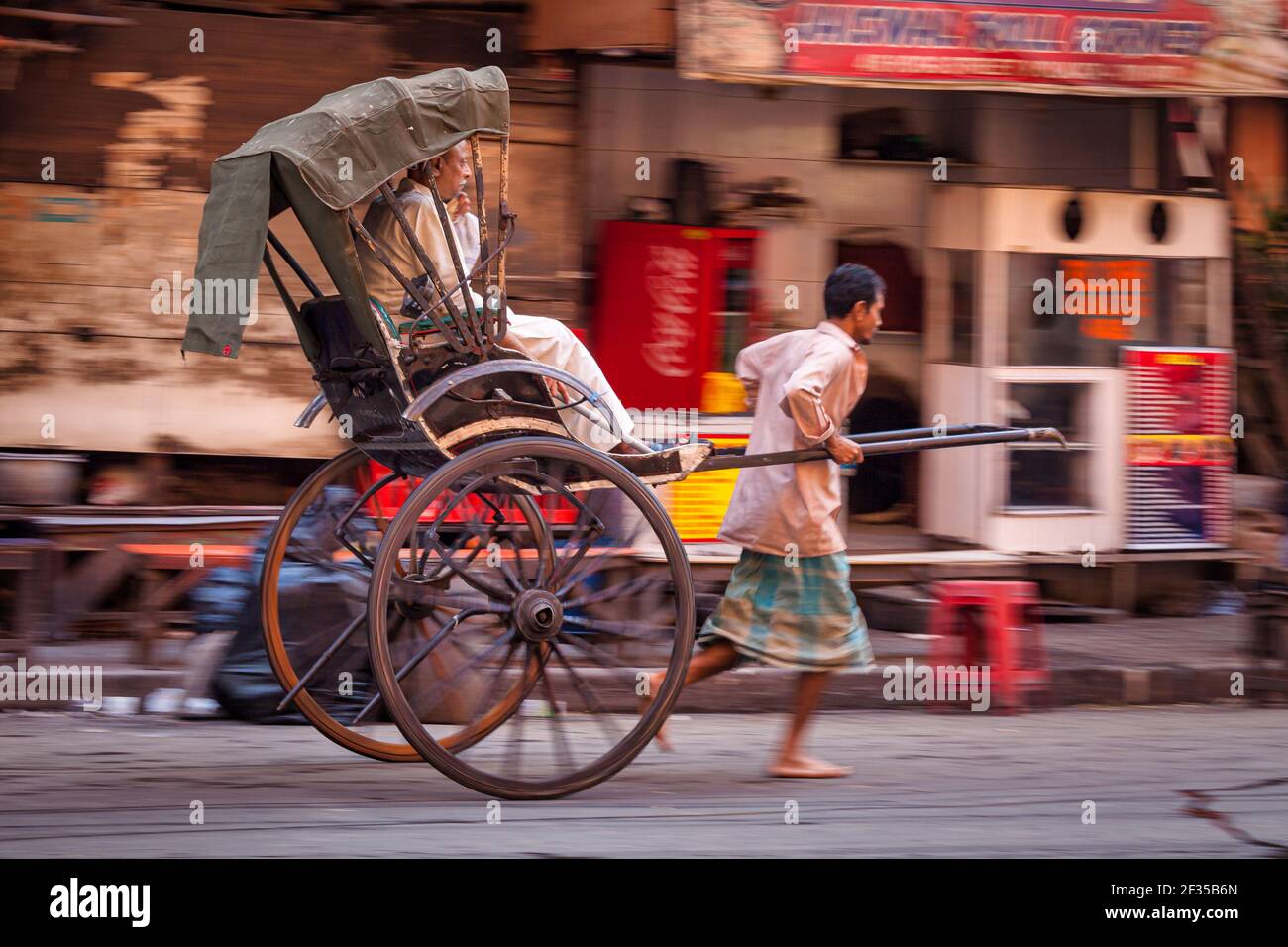 man-pulled-rickshaw-with-passenger-kolkata-west-bengal-india-2F35B6N.jpg