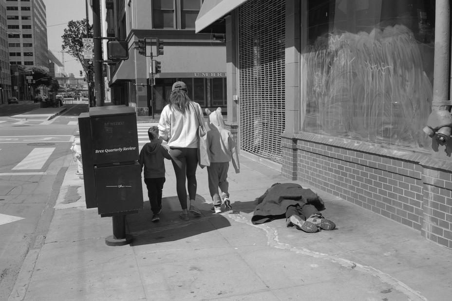 a family walks past a man laid out on the sidewalk