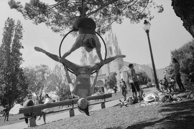 a woman hangs upside down in a hoop from a tree