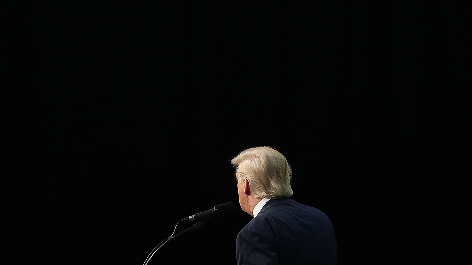 photo of Donald Trump's back at a microphone surrounded by black