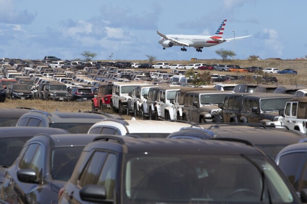 Unused rental cars are parked in an overflow lot at Kahului Airport in Kahului, Hawaii, on Aug, 14. 2023. So few tourists are coming to the Hawaiian island of Maui after last month's wildfires that restaurants and tour companies are laying off workers and unemployment is surging. State tourism officials initially urged travelers to stay away but now want them to come back so long as they refrain from going to the burn zone and surrounding area. (George F. Lee/Honolulu Star-Advertiser via AP)
