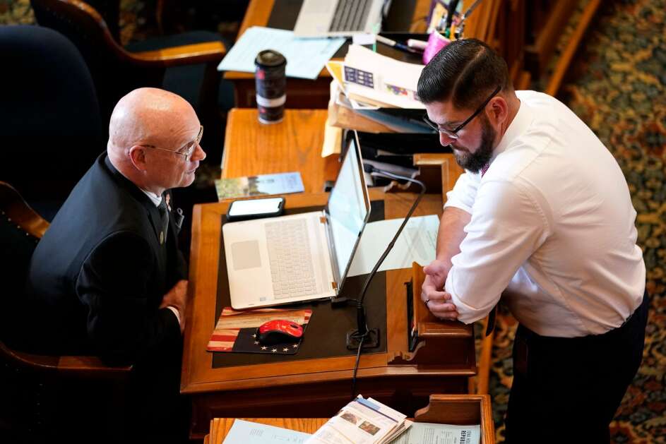 Rep. Steven Holt, R-Denison, talks May 22, 2022, with House Majority Leader Matt Windschitl, right, at his desk in the Iowa House chambers at the Iowa Capitol in Des Moines. (AP Photo/Charlie Neibergall))