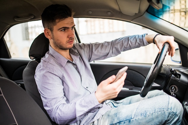 young-man-looking-mobile-phone-while-driving-car_231208-835.jpg