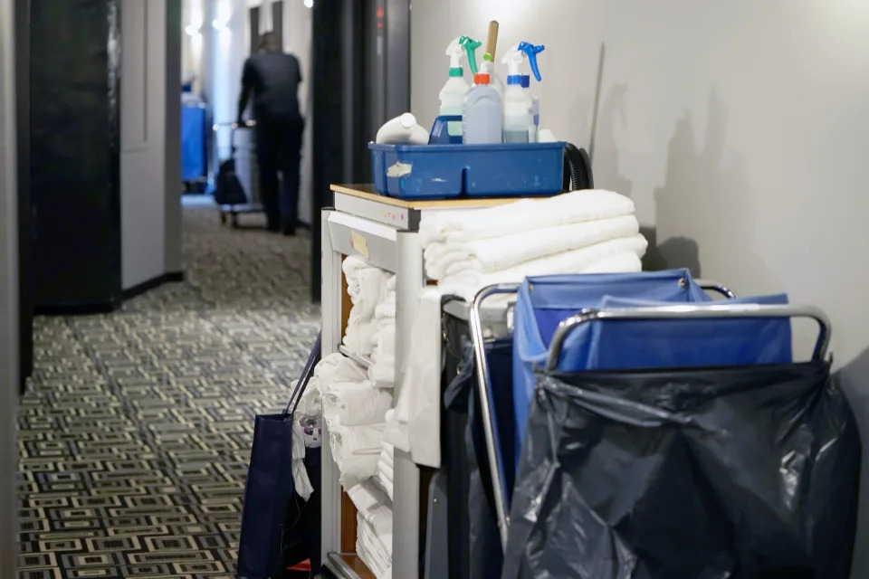 Hotel cleaning cart stocked with towels and cleaning supplies in a corridor