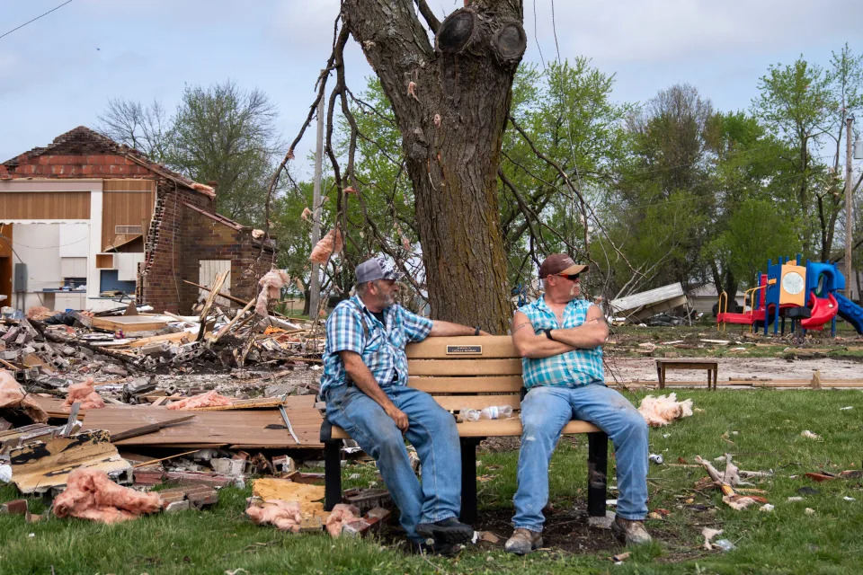 Buddy Allen (left) and Darrel Case (right) watch as residents clean up damage done by a tornado Saturday, April 27, 2024, in Tingley, IA.