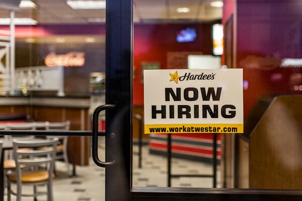 A help wanted sign hangs in the window at a Hardee’s fast-food restaurant.