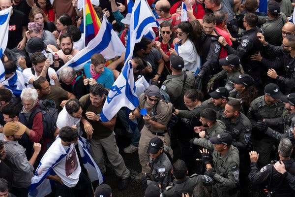 Protesters carrying Israeli flags, on the left, clash with police officers.