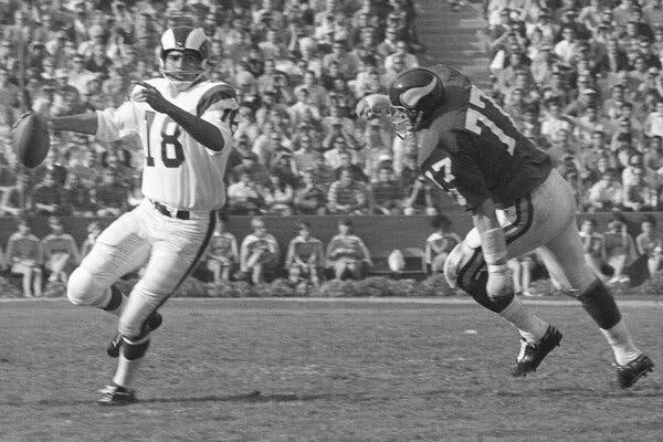 A black-and-white photo of Gabriel (wearing a white uniform with the number 18) in action, preparing to throw a pass as a defensive player closes in on him.