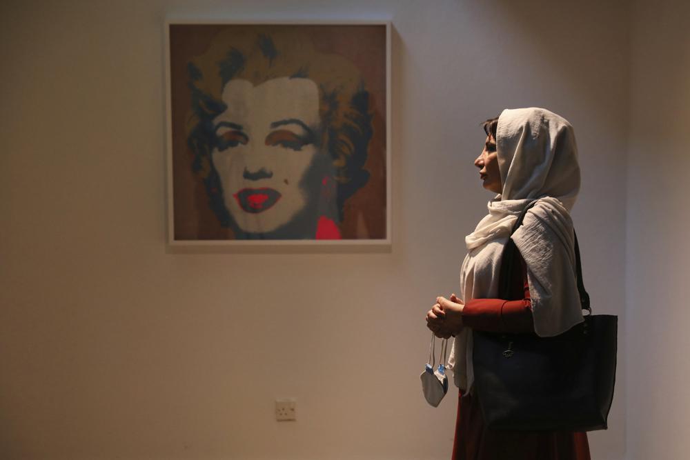Fatemeh Rezaei, a retired teacher, stands next to Marilyn Monroe portrait by American artist Andy Warhol at Tehran Museum of Contemporary Art in Tehran, Iran on Oct. 19, 2021. Iranians are flocking to Tehran's contemporary art museum to marvel at American pop artist Andy Warhol’s iconic work. (AP Photo/Vahid Salemi)